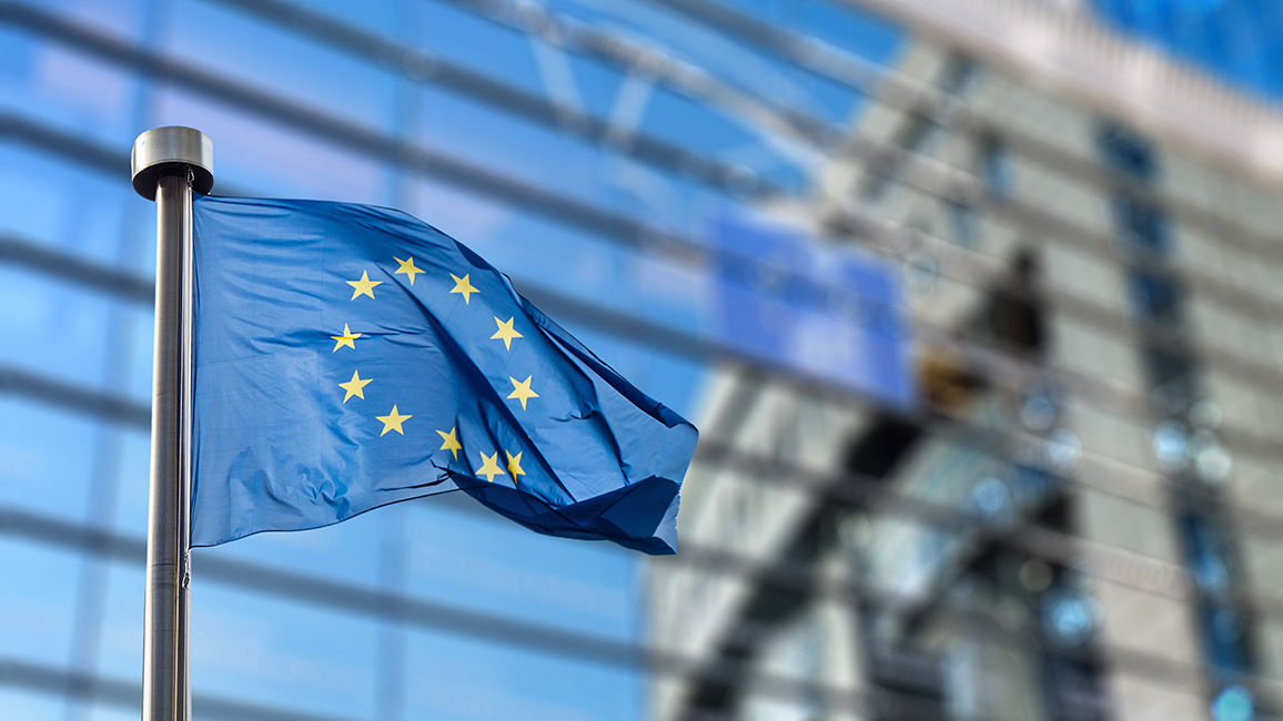Eine EU-Flagge weht vor einem Gebäude mit Glasfassade