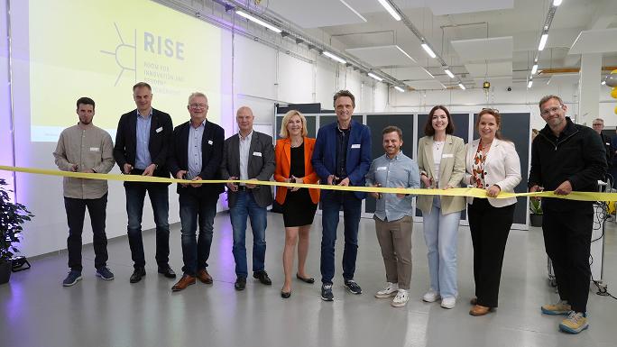 Etwa 10 Personen stehen in einer Reihe vor einem Eröffnungsband und schneiden es durch.