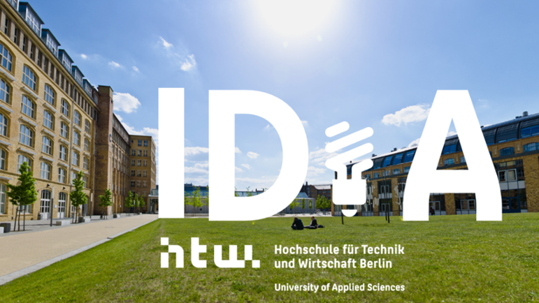 Eine grüne Wiese, links ein Gebäude, in der Mitte des Bildes der Schriftzug IDiA
