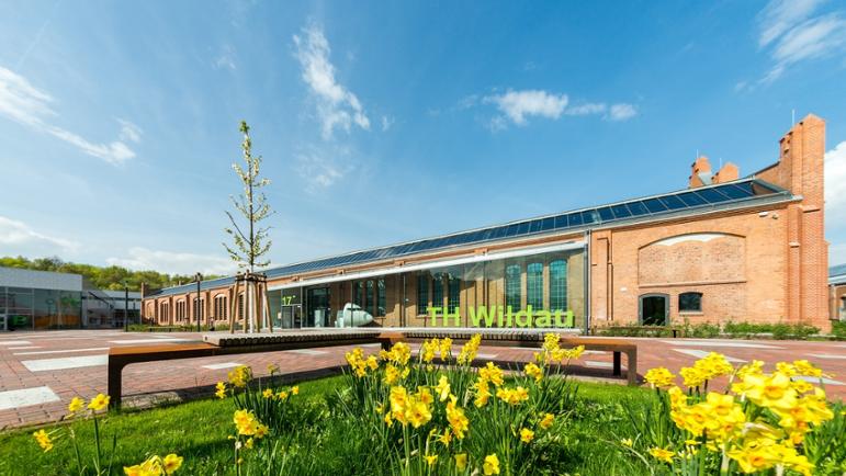 Rotes Backsteingebäude der TH Wildau, Blumenbeet im Vordergrund