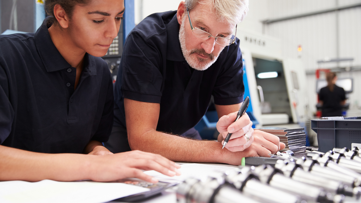 The picture shows an older man and a young woman discussing a project result.