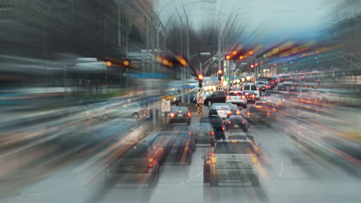 A washed out photo of numerous cars on a road, photographed from behind. The photo suggests the dynamics of road traffic.
